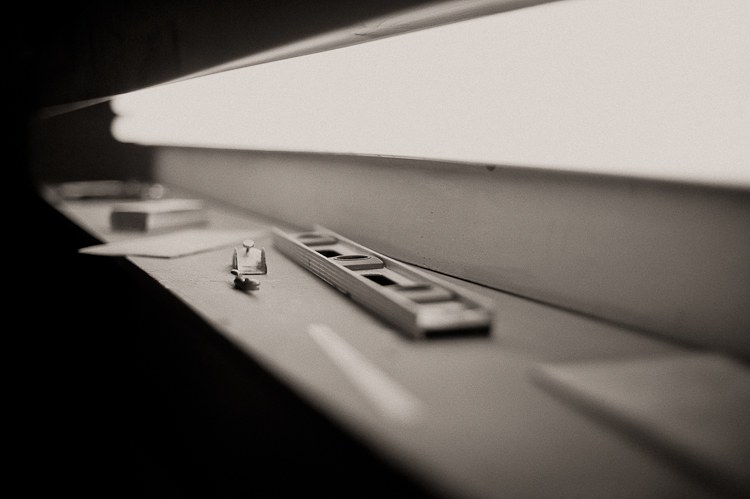 A level and shaping tools alongside a surfboard under the bay lights